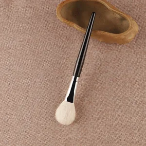 Close-up detailopname van professionele make-upkwast met zachte haren en zwarte steel.