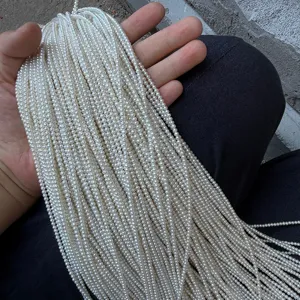 Primo piano dettagliato di fili di perle d'acqua dolce bianche da 2-3mm per il fai-da-te