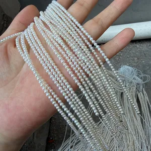 Veduta dettagliata di una mano che tiene più fili di mini perle bianche d'acqua dolce