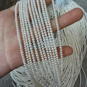 Primo piano di mini fili di perle coltivate d'acqua dolce naturali da 2-3mm in mano fai da te