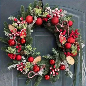 Couronne de Noël festive décorée de boules rouges, de baies et de cônes sur une porte sombre