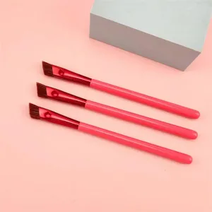 Pennello per sopracciglia angolato professionale con manico rosa e ghiera rossa.