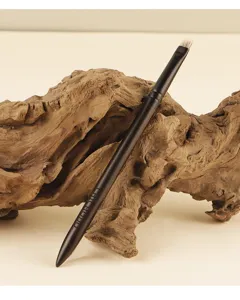 Detailed shot of an angled eyebrow makeup brush with wooden handle resting on driftwood.