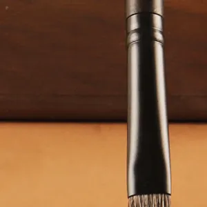 Professional angled eyebrow brush with copper ferrule and soft animal hair for precise filling.