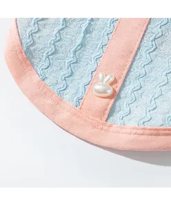 Gros plan détaillé de la chemise pour animal montrant le tissu seersucker et bouton lapin.