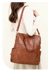 Detail view of the brown soft leather women's convertible backpack with metal zippers.