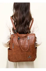 Detailed back view of women brown leather backpack, soft texture, metal zippers and straps.