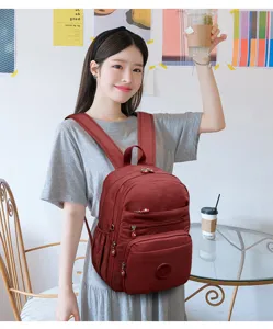 Detailed lifestyle scene showcasing a dark red nylon backpack worn by a smiling model indoors.