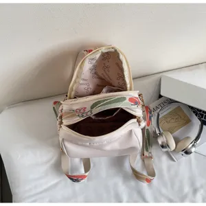 Vista dettagliata dello zaino casual beige con spallacci ricamati e tasche con cerniera.