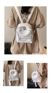 Detailed view of white leather backpack showcasing smooth zipper pockets and soft straps.