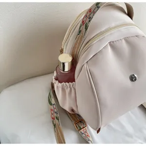 Vista di dettaglio di un elegante zaino casual beige da donna con spallacci ricamati.