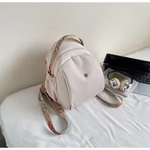 Dettagli dello zaino casual beige con spallacci ricamati e tasche con cerniera.