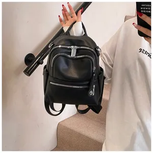 Close-up detail of stylish black PU leather mini backpack with metal zippers and top handle.