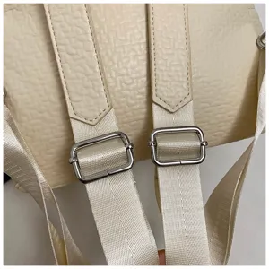 Close-up detail of beige backpack straps with durable fabric webbing and metal adjusters.