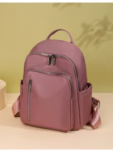 Detail view of stylish pink waterproof oxford fabric backpack with multiple zipper pockets.
