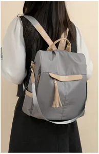 Sac à dos gris élégant pour femme avec bretelles beiges et pompon, sac de voyage décontracté.