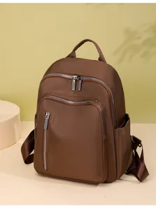 Premium brown oxford cloth backpack detail showing durable metal zippers and multiple spacious pockets.