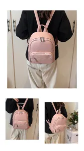 Pink leather backpack detail view showing soft texture, metal zippers and front pocket.