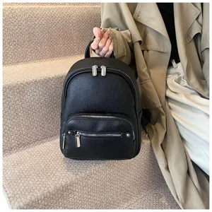 Black leather backpack detail view with soft texture and metal zippers on stairs.