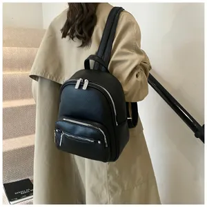 Detail view of black faux leather women backpack worn on model, showing texture and zippers.