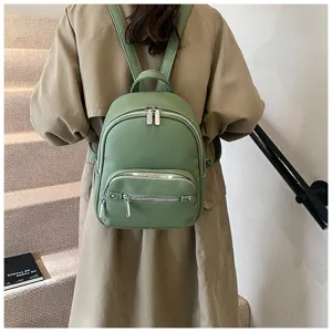 Women's soft leather backpack detail view showing green texture, zippers, and structure.