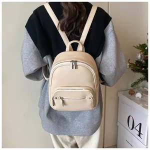 Close-up view of a soft PU leather backpack in beige, showcasing front zipper pocket and texture.