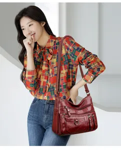 Dettaglio della borsa a tracolla da donna in morbida pelle PU con tasche multiple in rosso scuro.