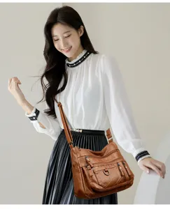 Primo piano della elegante borsa a tracolla in pelle PU marrone con tasche multiple.