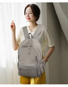 Primo piano del elegante zaino casual grigio indossato da un modello, che mostra tasche.