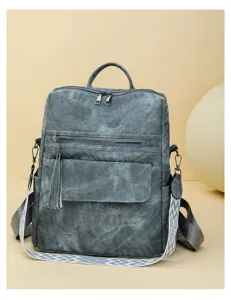 Vintage soft leather backpack detail, featuring front tassel zipper pocket and patterned strap.