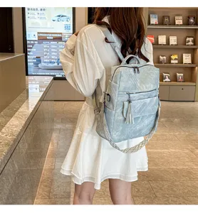 Detailed view of casual soft leather backpack with tassel and patterned strap in indoor scene.