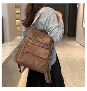Detail view of a retro women's soft leather backpack with tassel and wide strap for travel.