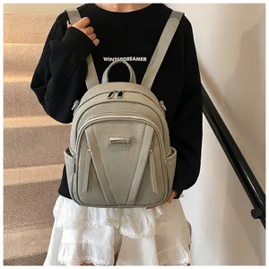 Detail view of a stylish grey leather backpack featuring multiple pockets and metal zipper closures.