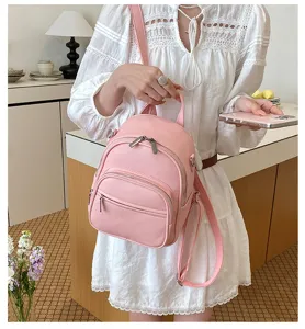 Close-up detail shot of a stylish pink casual leather backpack in an indoor room setting.