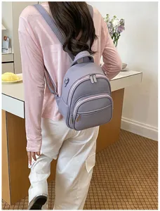 Detail shot of casual purple leather backpack worn by model, showing zipper pockets and style.