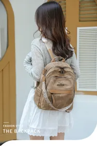 Détail de sac à dos en toile rétro avec patchwork en cuir marron, grands compartiments et bretelles.
