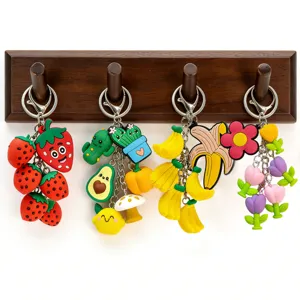 Detailed shot of 3D silicone cute fruit and plant keychains hanging on a wooden wall hook.
