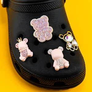 Gros plan détaillé de charms de chaussures ours en strass sur des sabots noirs présentoir.