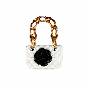 Detail view of miniature quilted bag shoe charm with black camellia flower and chain handle.