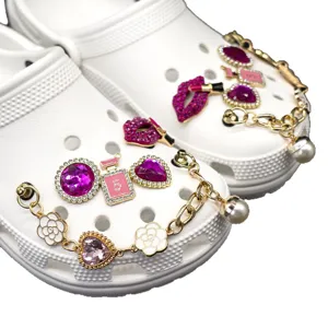 White clogs with luxury pink rhinestone charms, camellia and chain shoe accessories.