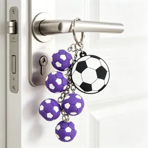 3d soccer ball keychain detail view, purple and black white football charms hanging on door.