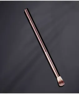 Professional makeup brush with sleek metallic handle for precise highlighter application.