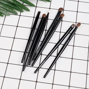 Set zwarte make-up kwasten voor oogschaduw en details, platte weergave op rasterachtergrond.