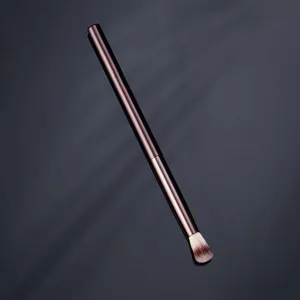 Professional makeup brush with metallic handle and flame-shaped bristles for precise highlighting.