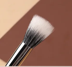 Gros plan de détail d'un pinceau de maquillage professionnel aux poils bicolores.