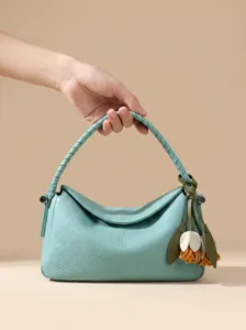 Elegante borsa a tracolla in pelle verde chiaro con manico intrecciato e ciondolo a fiore.
