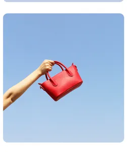 Gedetailleerd overzicht van de minimalistische rode lederen handtas met elegante textuur.