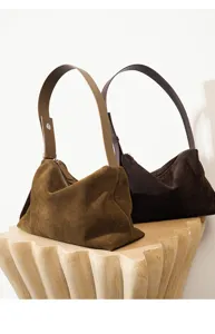 Detalle de bolso de hombro de ante marrón con textura de cuero suave y cremallera elegante.