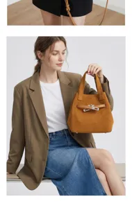 Detailed view of brown suede top handle handbag with iconic metal turn-lock closure hardware.