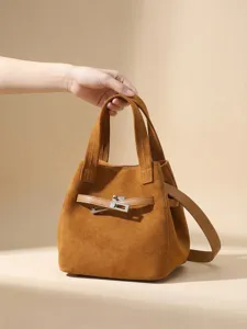 Brown suede bucket bag for women, luxury top handle handbag with metal lock and shoulder strap.